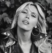 Outdoor portrait of a woman in a studded leather jacket and large hoop earrings.
