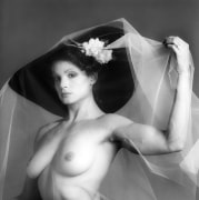 Portrait of Lisa Lyon, nude except for hat and veil, in 3/4 view.