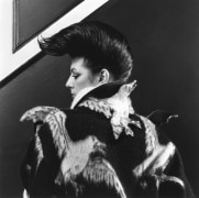 Woman shown from behind wearing a designer seagull coat, her face is in profile and her hair is quaffed.