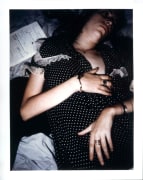 Patti Smith lying on bed in polka dot dress.