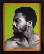 Milton Moore from the chest up looking over his right shoulder in front of a bright green background and with an orange border in a black frame.