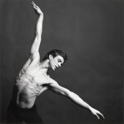 Shirtless man spreading his arms out in a graceful dance pose.