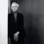 Andy Warhol leaning against a wall.