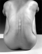 Nude woman sitting from behind, back bent.