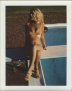 Sylvia Myles wearing a bikini, sitting on a diving board looking off to the left.