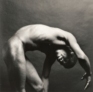 Black Male nude leaning towards his feet, one arm over head.