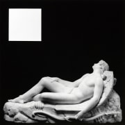 Statue of sleeping cupid reclining with white square in upper left corner.