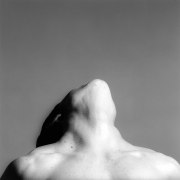 Head and shoulders view of a muscular woman tilting her head backward so that her face is not visible.
