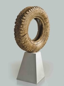A large tire, scaled up and hand carved out of wood.