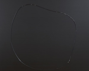 A roughly circular shape on a black ground. The shape is make with a single line of black paint.