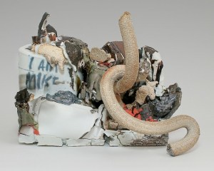 A sculpture of mixed stoneware. There are several serpentine tube shapes, silver lusters and seemingly molten elements that appear to drip over. At left is a shape that resembles a paint can with the works "I AM MIKE" written upon it.