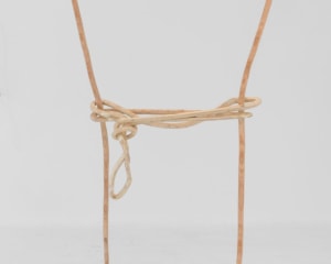 A plywood sculpture that is meant to look like a single carved line. The line describes a silhouette of a rectangle, which seems to have a rope strung and tied around the center.