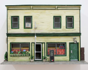 A photograph of the facade of the building that housed Callicoon Fine Arts in Callicoon, NY, made from foam core and paper. It is a yellow building with green trim and doors. There is an Italian restaurant on the first floor.