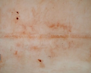 A photograph of a site-specific installation on the wall in red, with text.