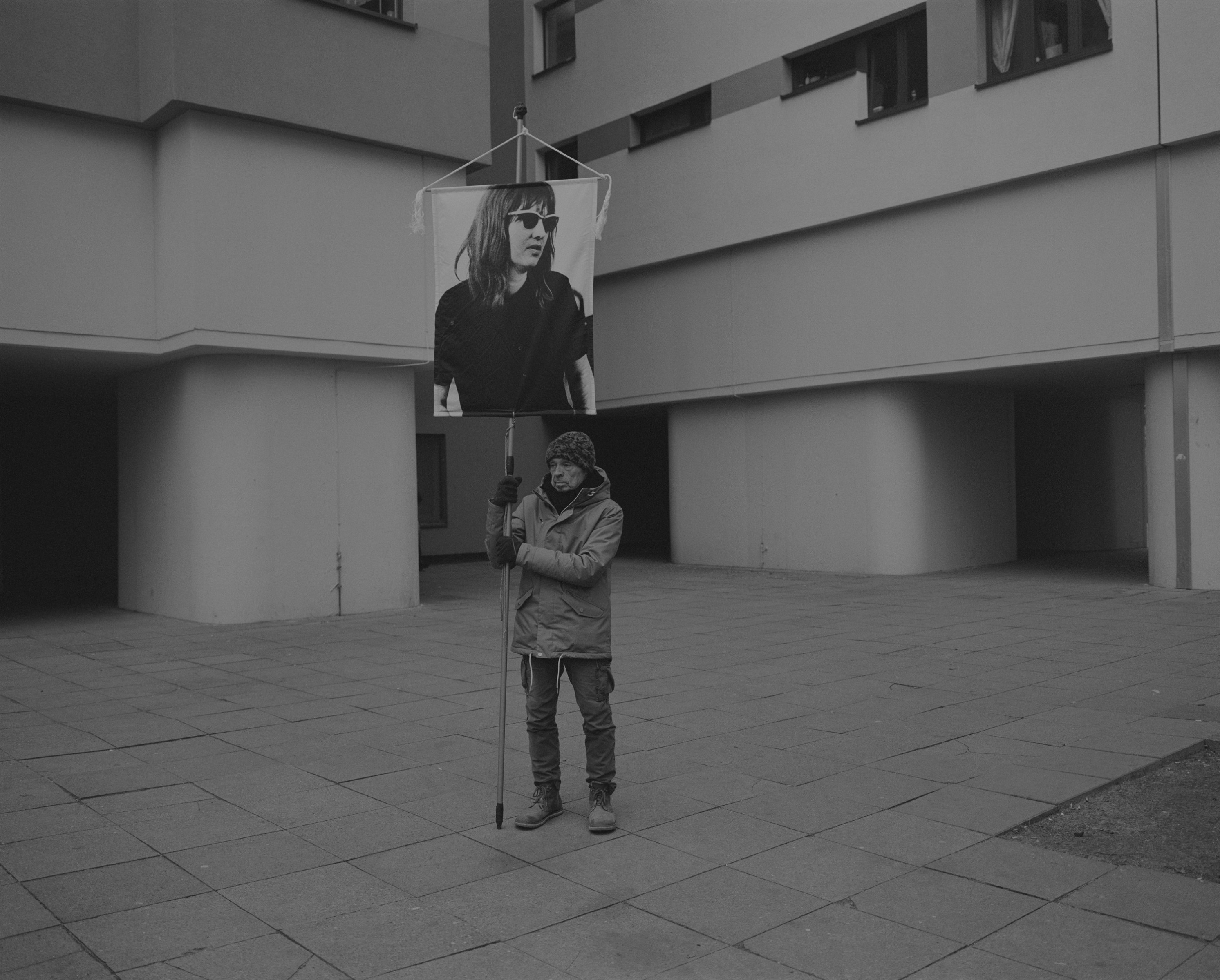 Daniel Joseph Martinez At an entrance of one of the apartment towers at Märkisches Viertel. The district where it's located is called "Reinickendorf" one of the districts in the so called "Speckgürtel"/ exurbs of Berlin. Quite a poor neighborhood., 2017 Medium format black & white film printed digitally on Hahnemule Fine Art Baryta, Gloss 315gsm 60 x 72 in (152.4 x 182.88 cm)