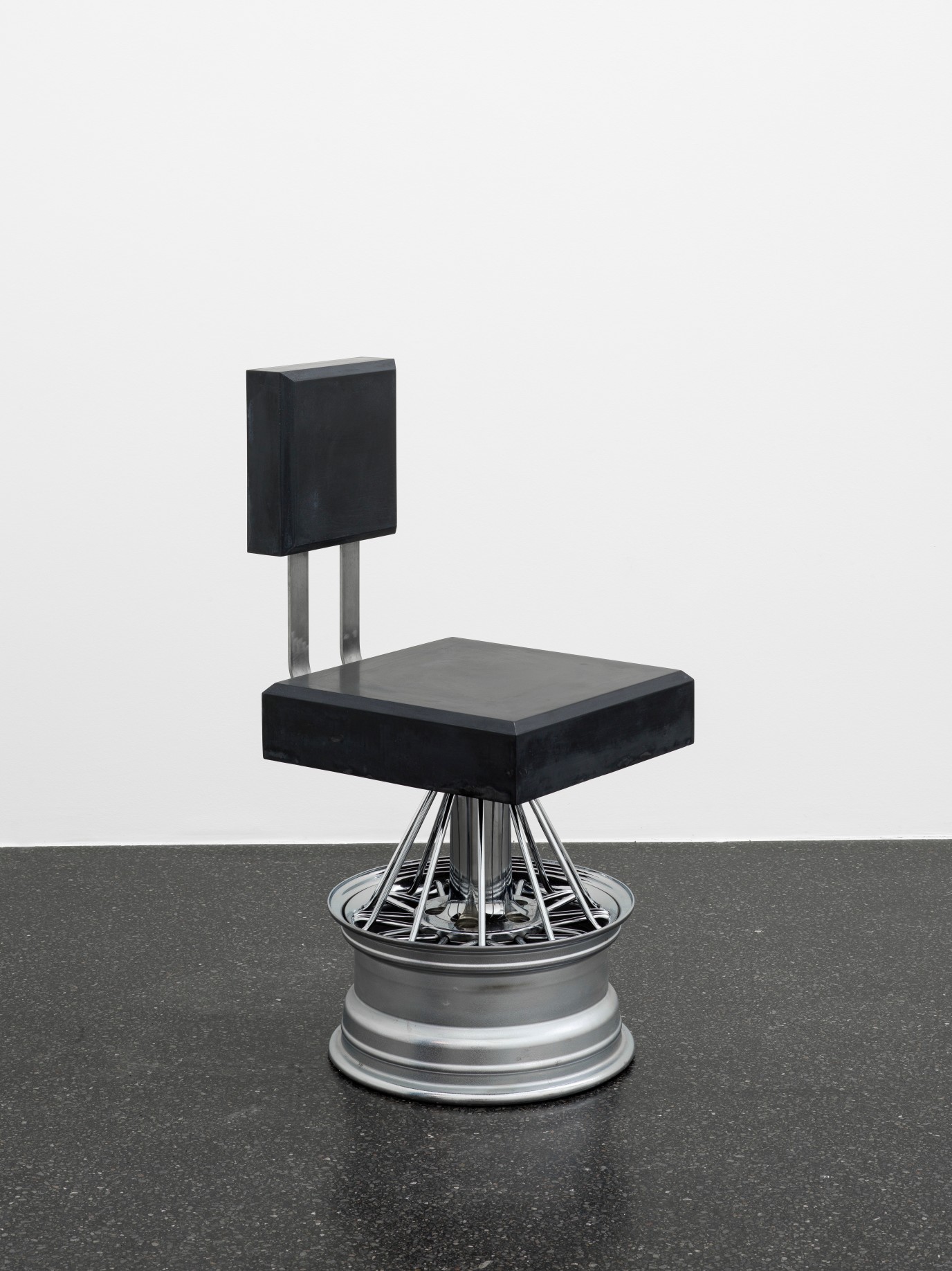 Dozie Kanu, Chair [ iii ] (Dark), 2022, Poured concrete, steel, rims, Ed. of 7 (+ 2 AP), 91.4 x 41.9 x 52.1 cm. Courtesy the artist and Galerie Francesca Pia