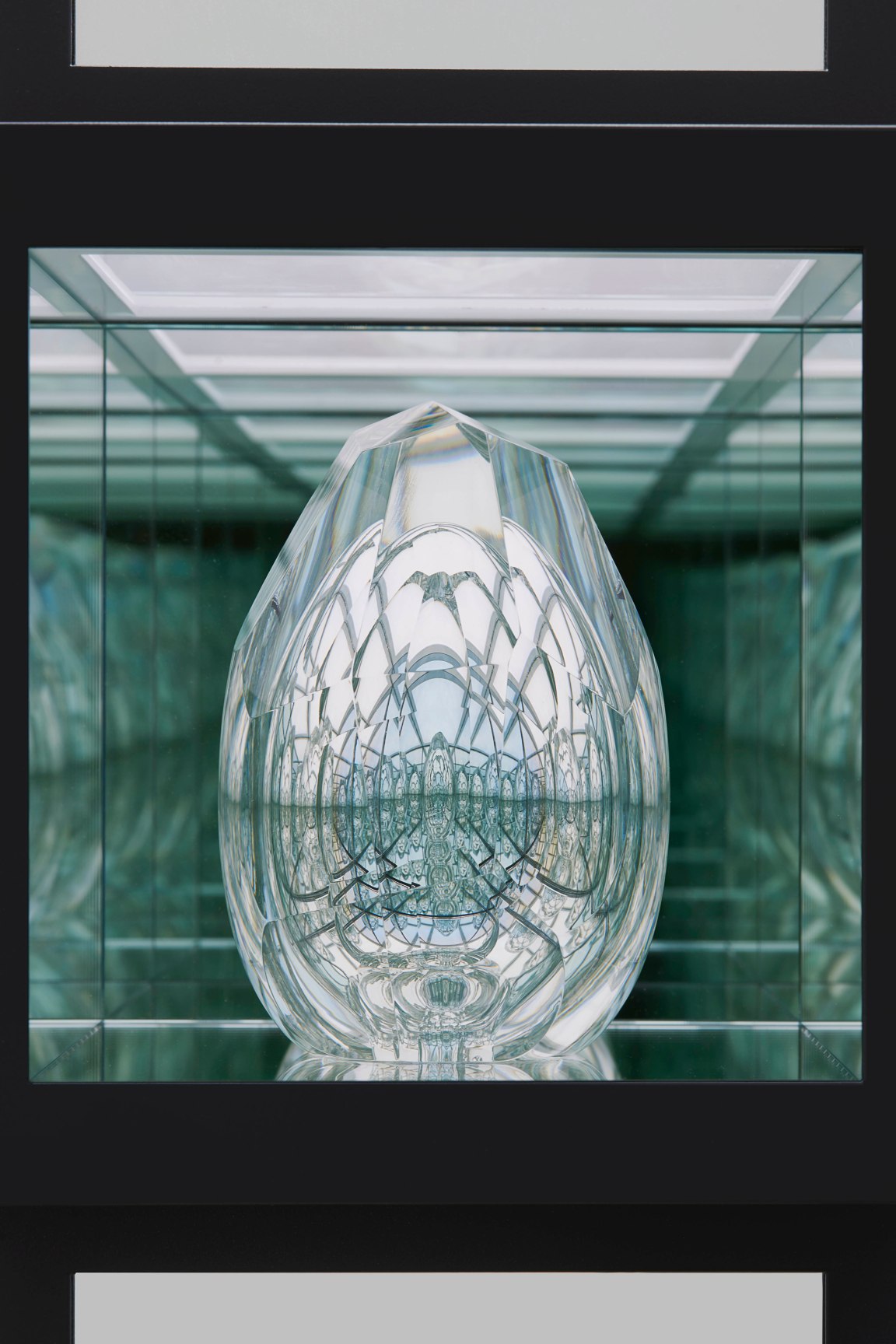 Close-up view of a lit in-laid box with reflective glass sculpture inside