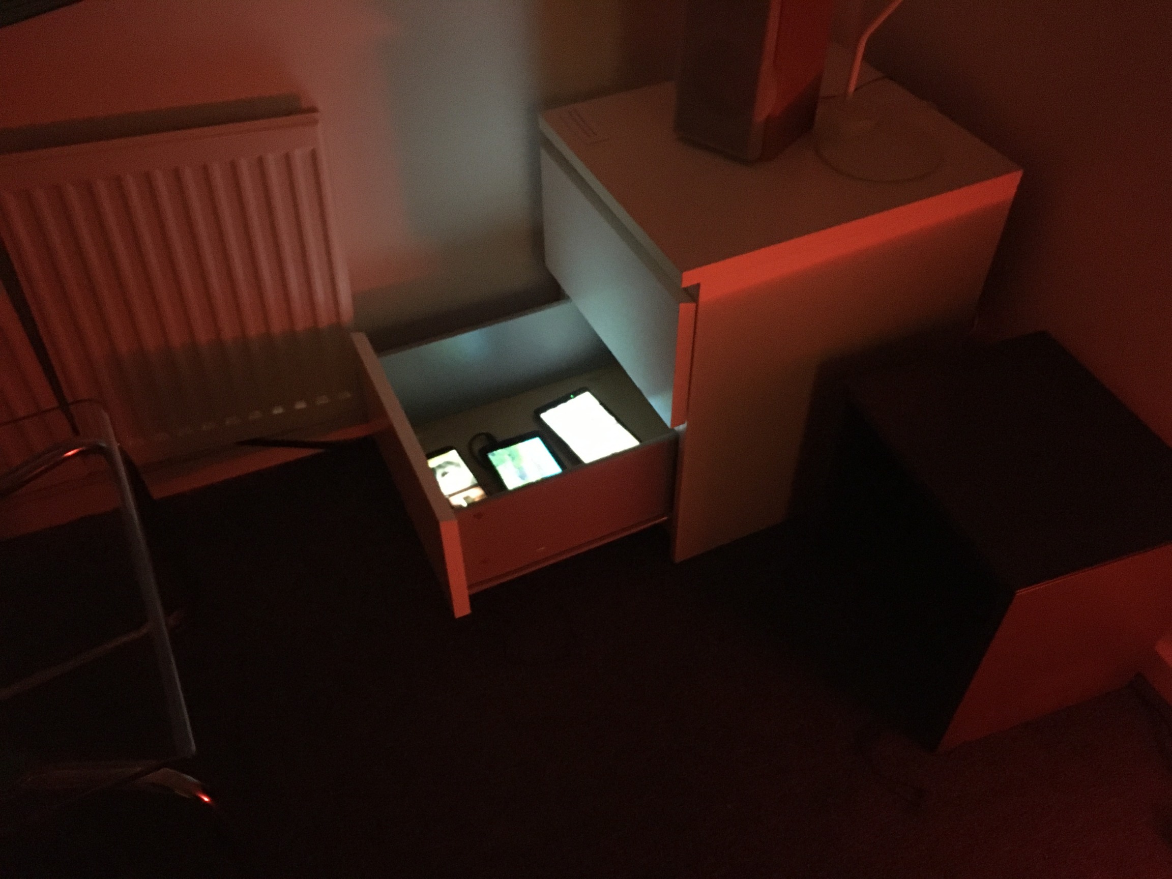 Image of an artwork installation that features 3 mobile phones inside a desk drawer