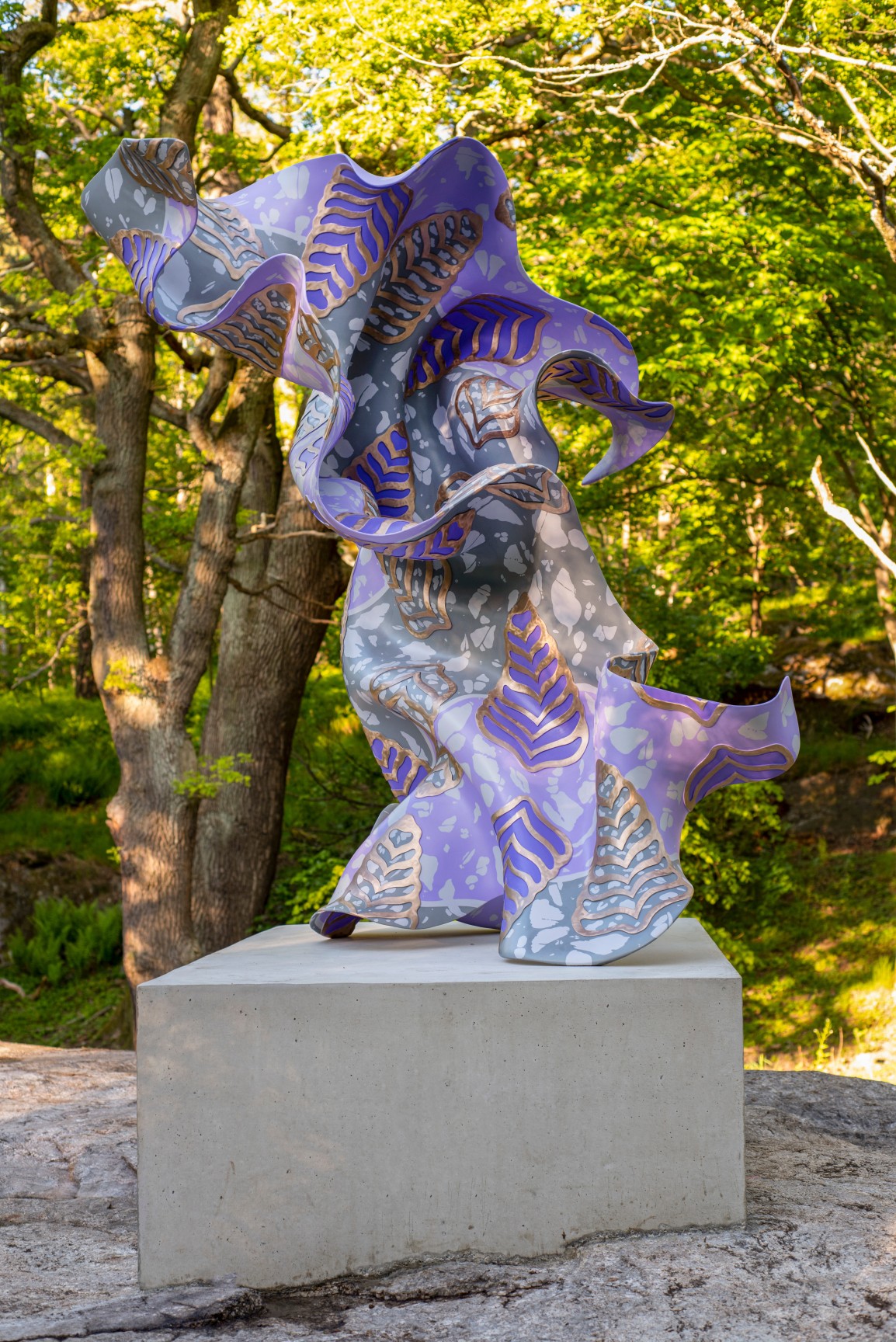 A large, purple, bronze, gestural sculpture sitting atop a rectangular base