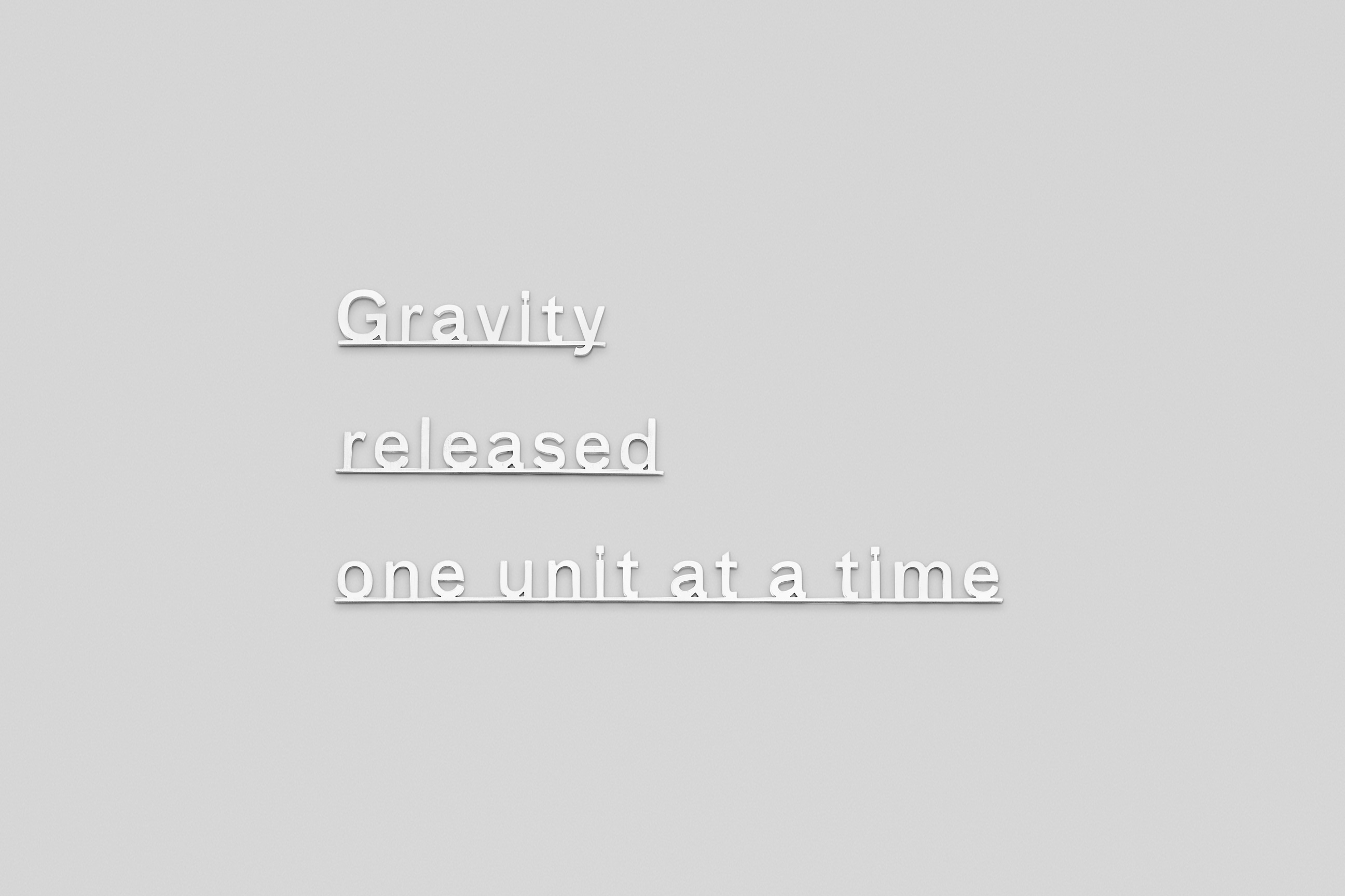 text made of Micro waterjet-cut sterling silver attached to a plain white wall