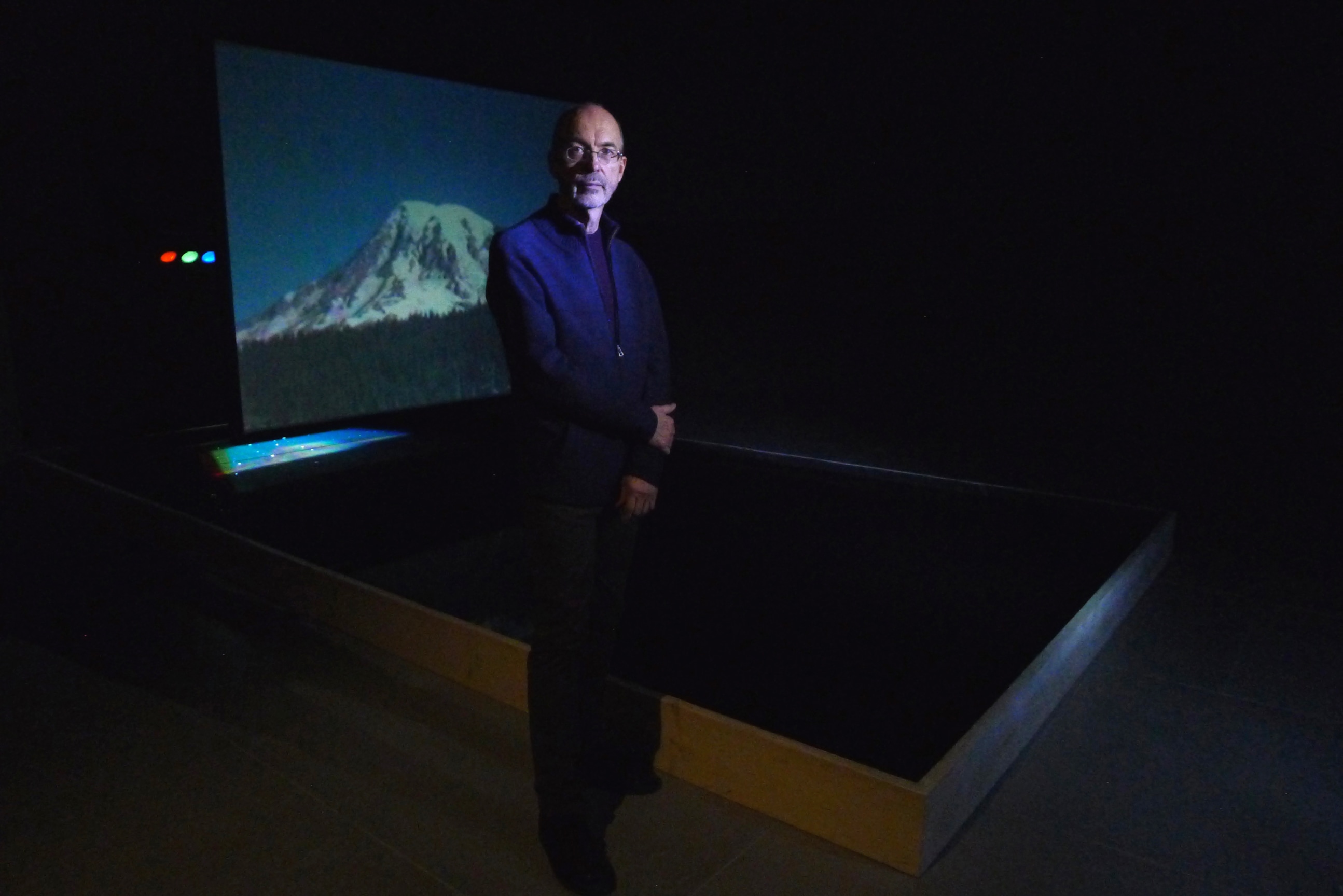 Bill Viola standing in front of one of his videos