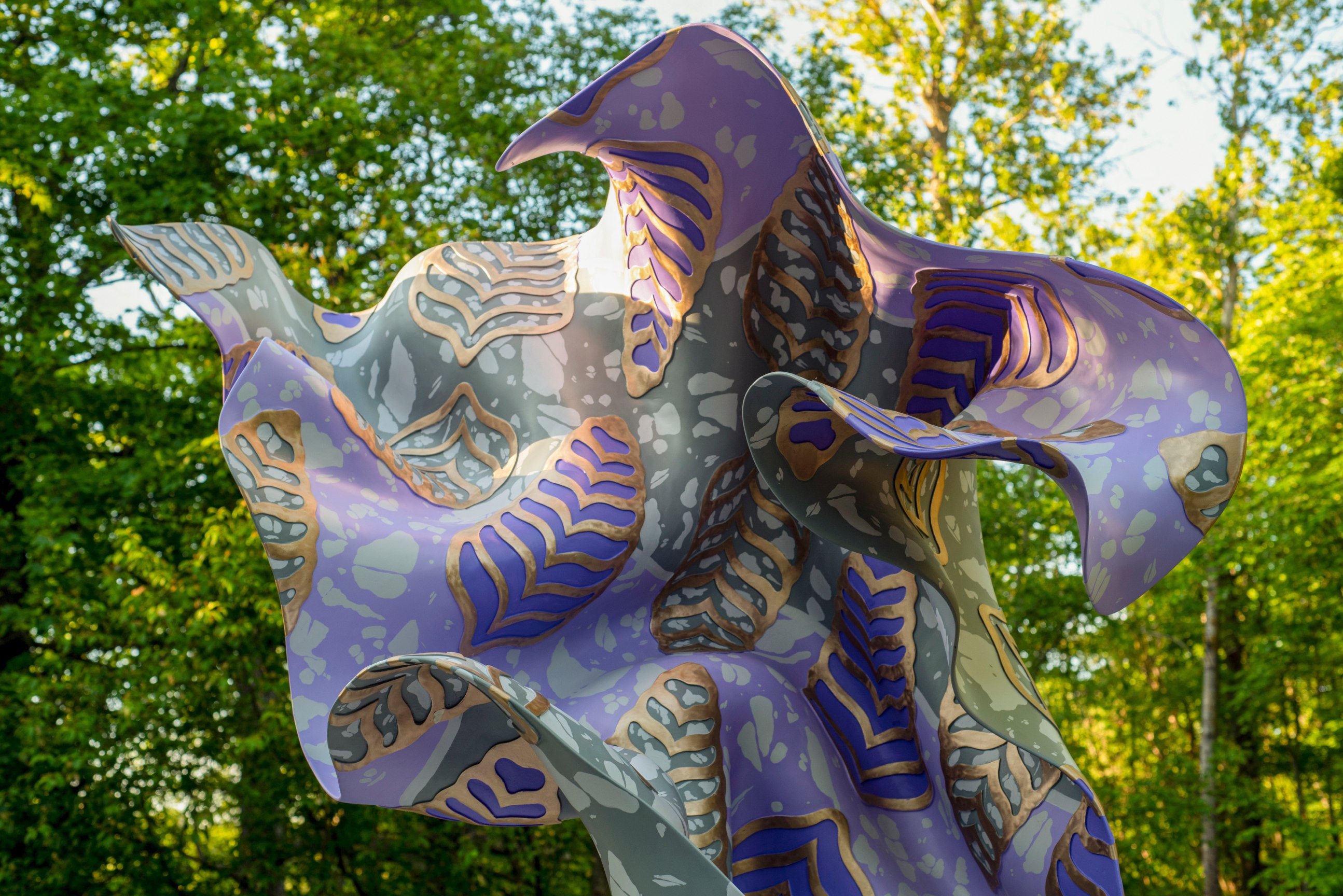 A large, purple, bronze, gestural sculpture sitting atop a rectangular base