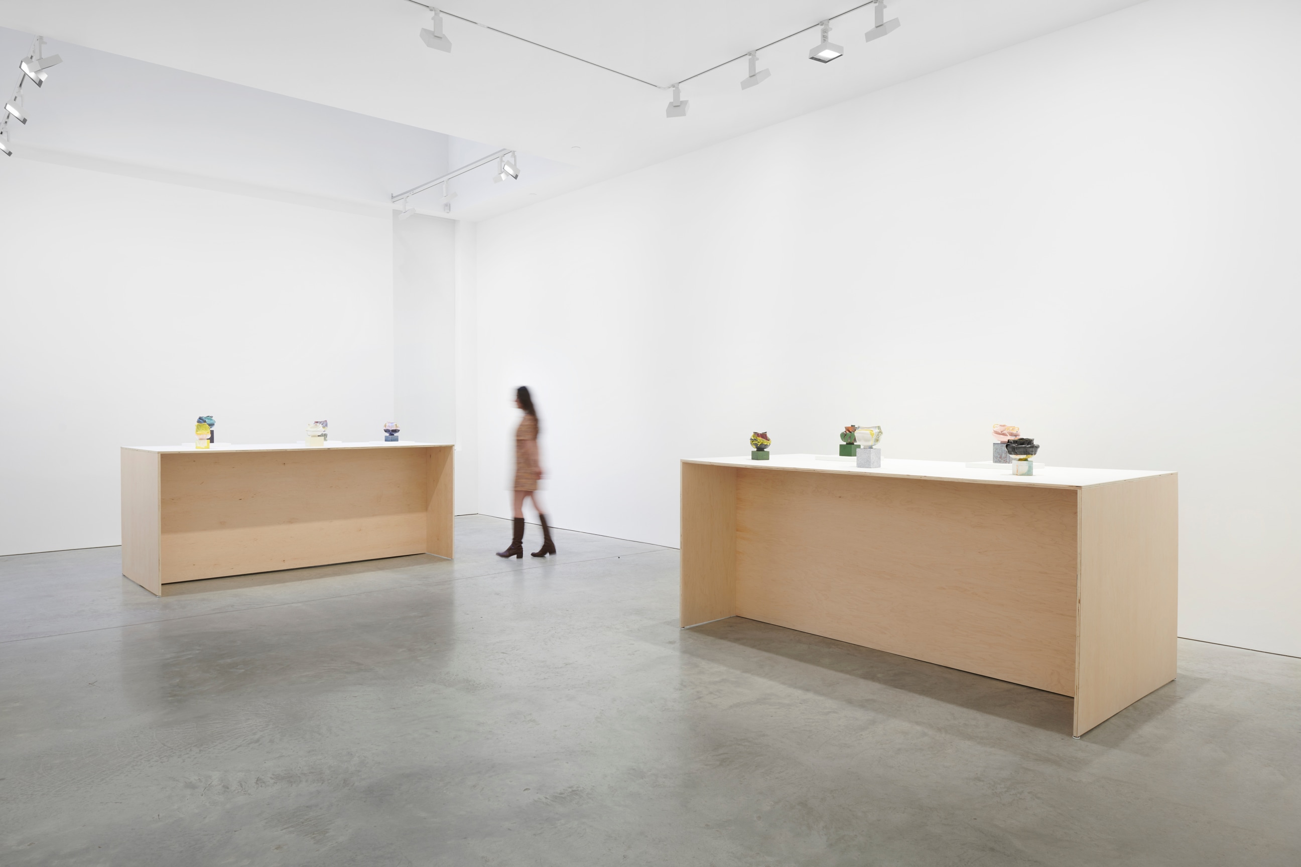 person walking between two tables with small artworks