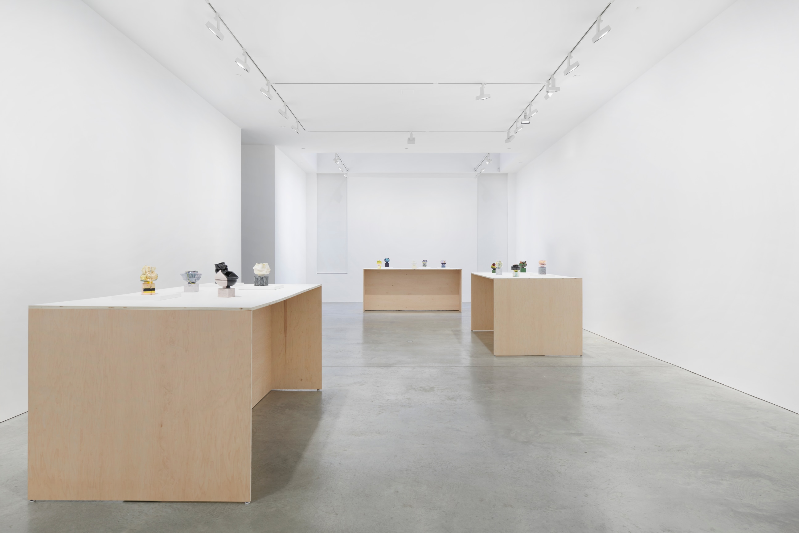 long gallery containing tables with small artworks