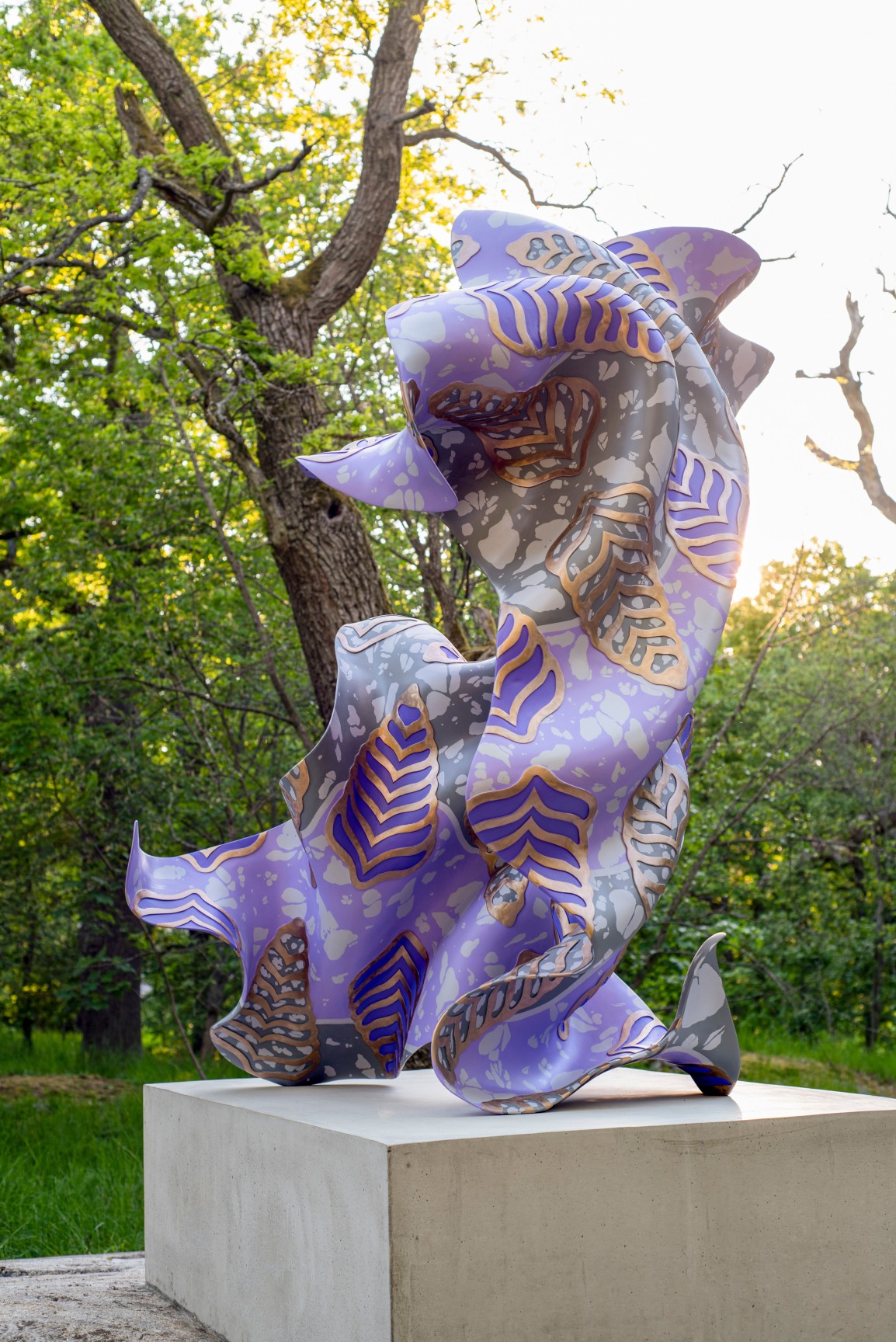 A large, purple, bronze, gestural sculpture sitting atop a rectangular base