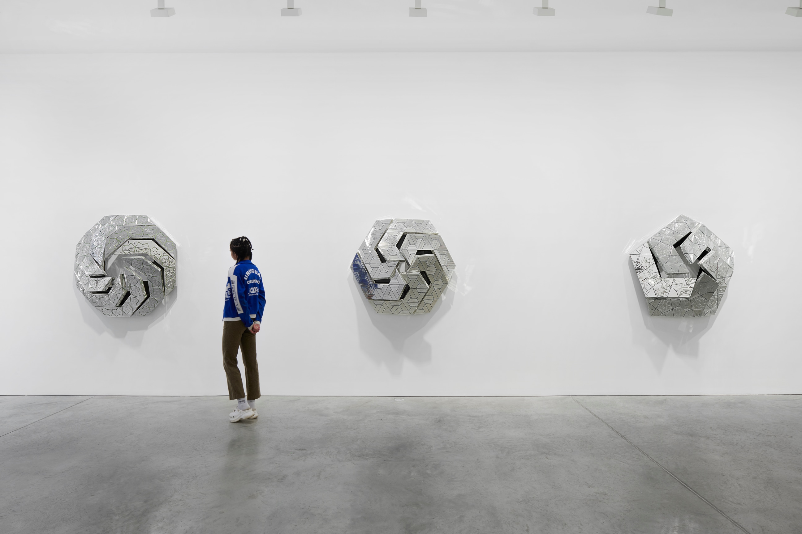 person observing one of three geometric, glass artworks