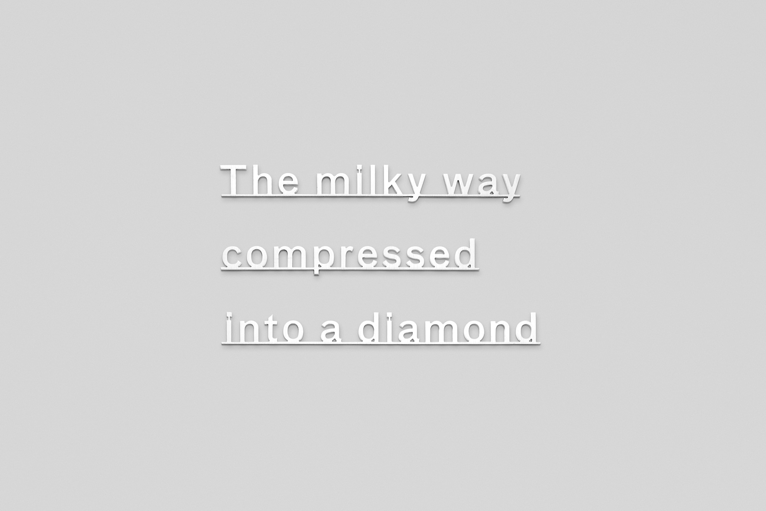 text made of Micro waterjet-cut sterling silver attached to a plain white wall