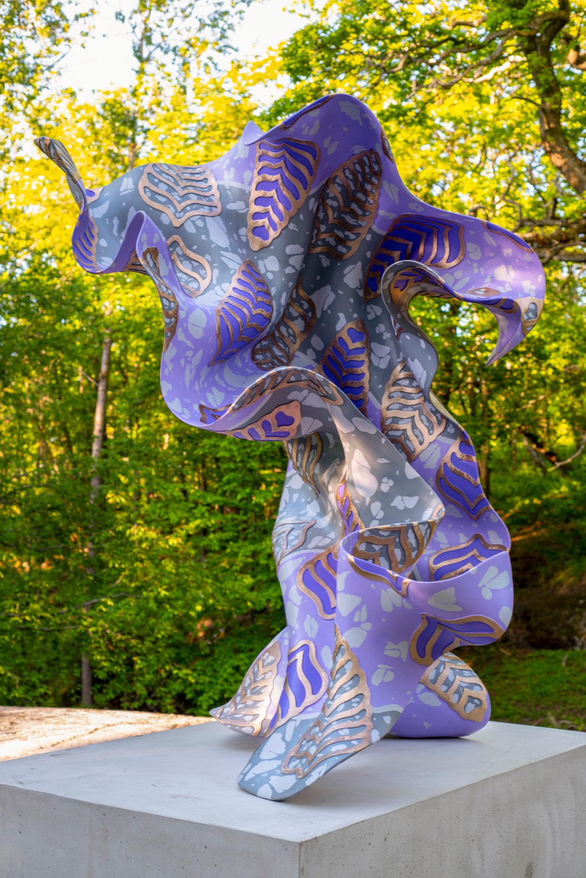 A large, purple, bronze, gestural sculpture sitting atop a rectangular base