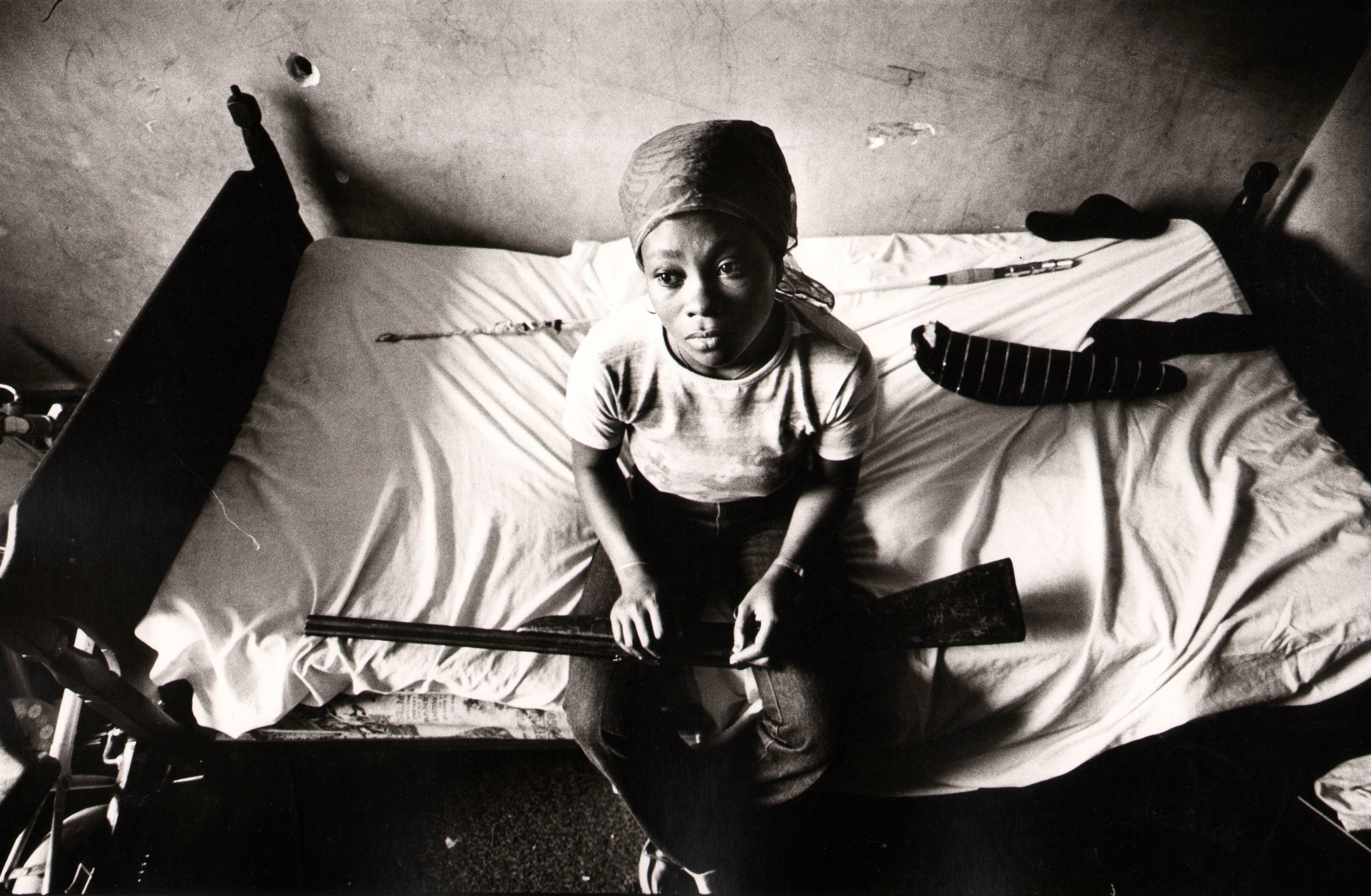 5. Eli Reed, Female resident sitting with only a nonworking rifle for protection, &ldquo;Pink Palace&rdquo; housing project, San Francisco, California, 1981