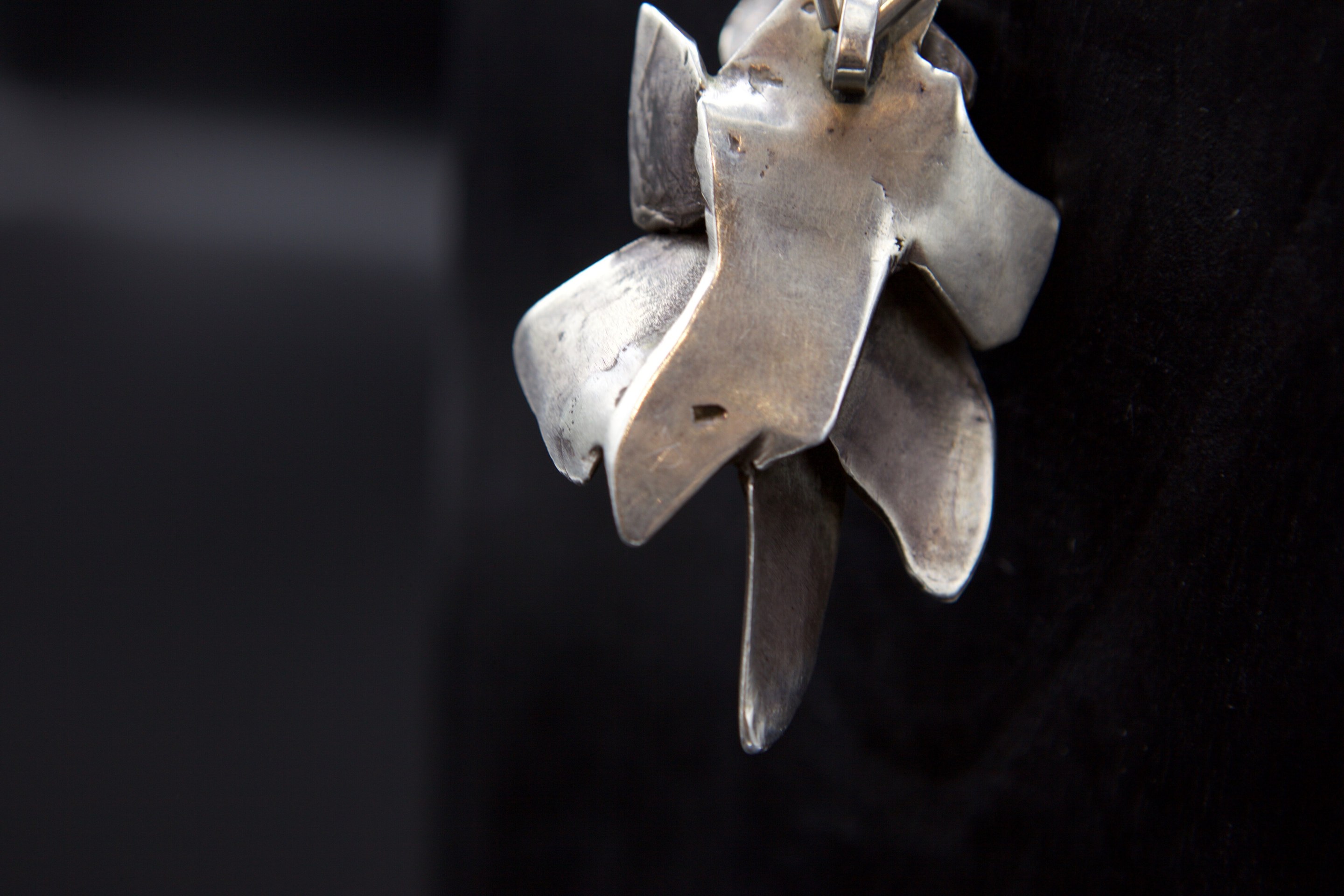 Alicia Penalba's necklace, close up view of back of pendant showing makers mark