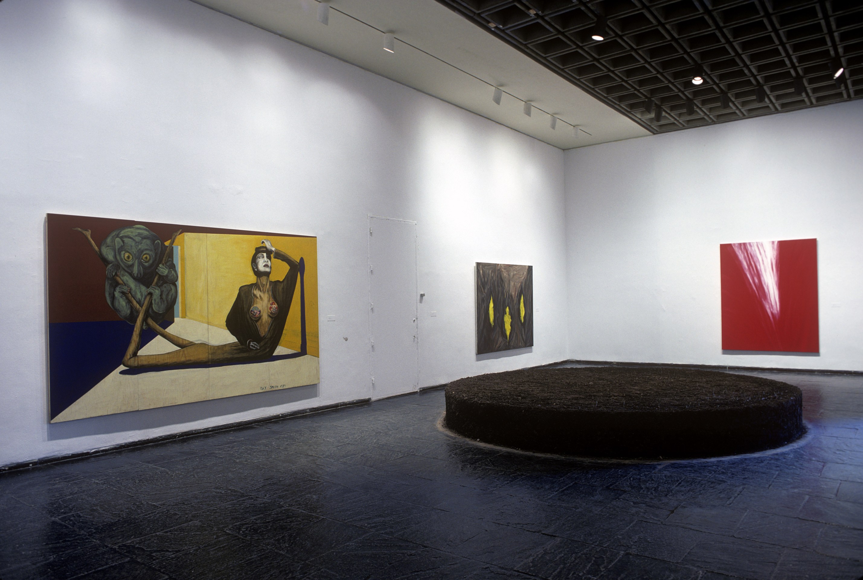 Installation view of&nbsp;1989 Biennial Exhibition&nbsp;(Whitney Museum of American Art, New York,&nbsp;April 18-July 16, 1989). From left to right:&nbsp;Ray Smith,&nbsp;El Plagio, 1989; Martha Diamond,&nbsp;Three Lights, 1988; Martha Diamond,&nbsp;Red Light, 1988; On floor:&nbsp;Meg Webster,&nbsp;Earth Stage, 1989. Photograph by Geoffrey Clements, courtesy the Whitney Museum of American Art, New York
