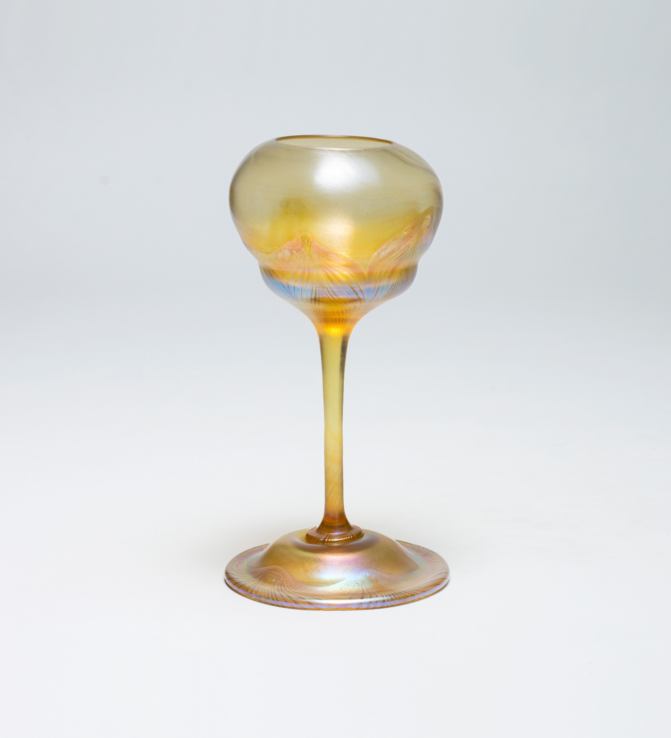 an early tiffany glass flower form vase from the 1890s in transparent yellow-gold glass with delicate decoration of swags in rainbow iridescence at the foot and on the flower cup