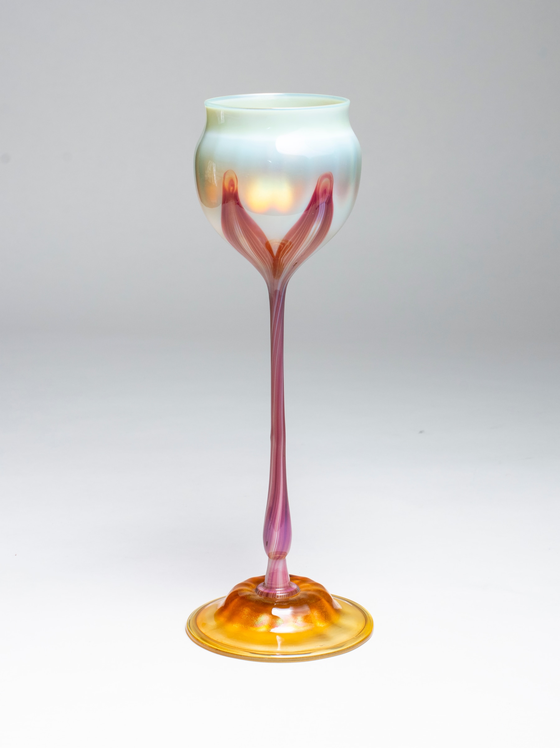 an early tiffany favrile glass flower form, the creamy white flower cup supported by a stem of deep red glass, on a domed foot. red was an unusual and rare color in blown tiffany glass,