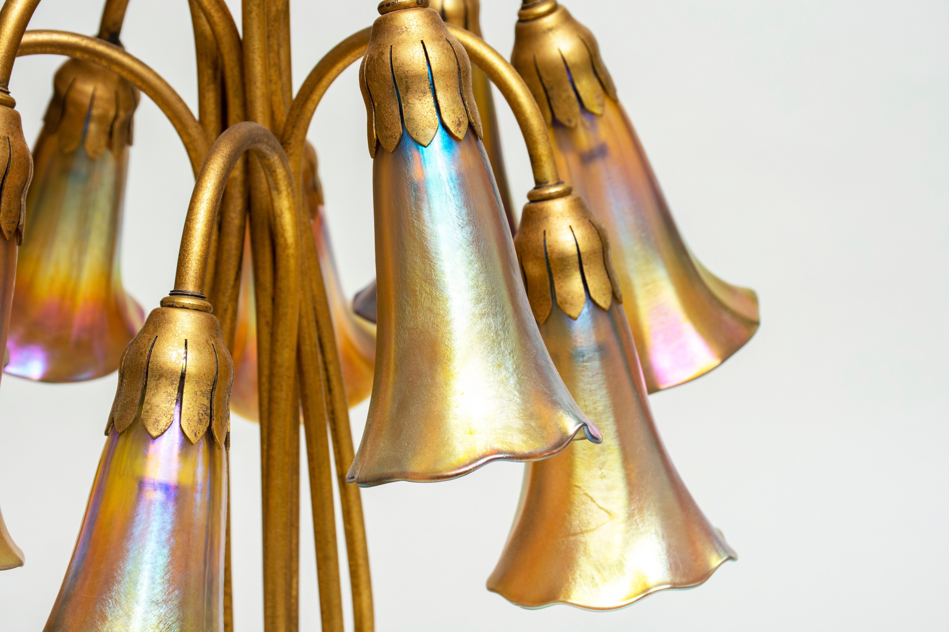 the tiffany favrile glass lily shades up close showing their bright vibrant golden yellow color and the silvery rainbow surface iridescence which is characteristic of tiffany glass