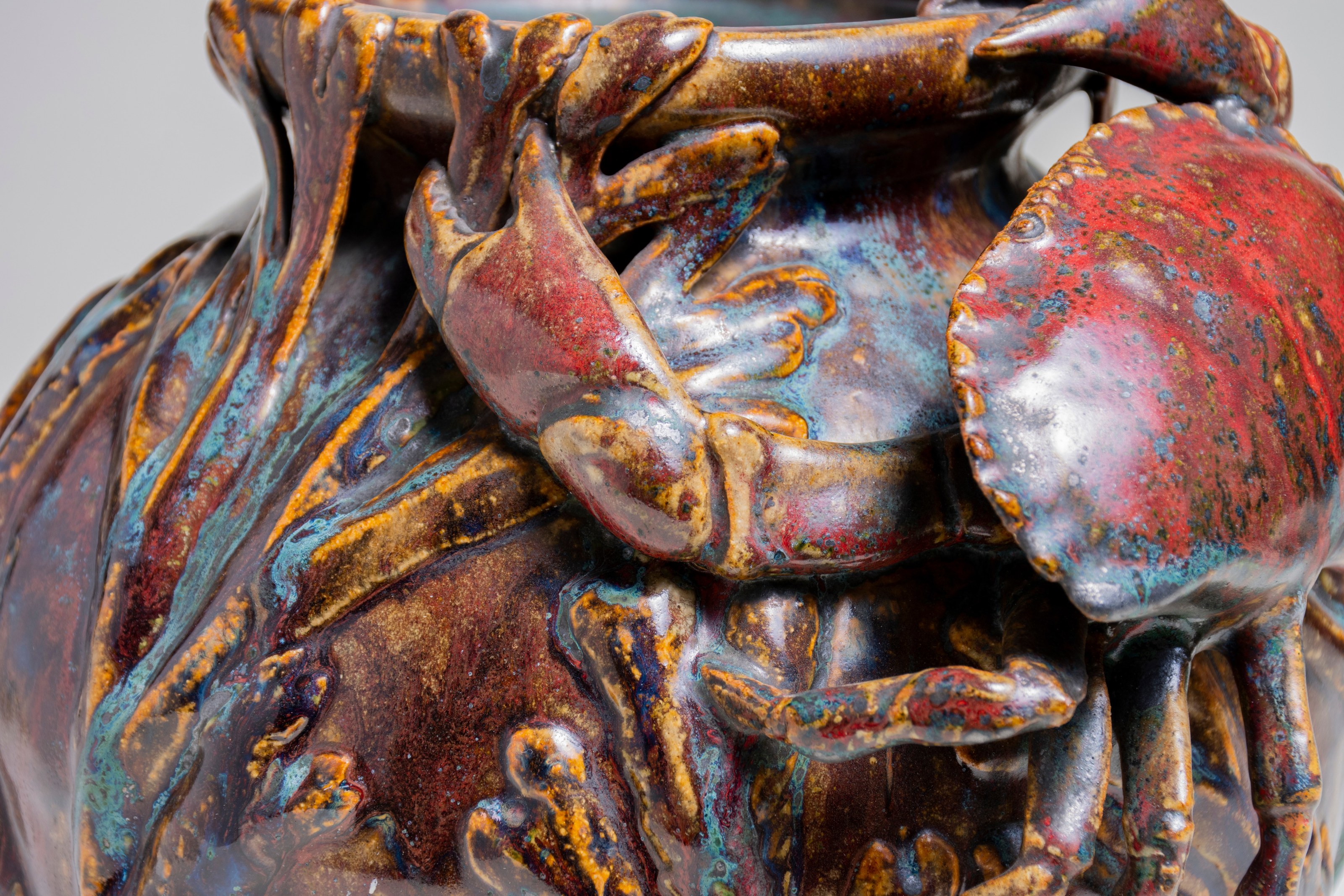 detail of the rouge dalpayrat glaze, also called oxblood or sang de boeuf, showing the rich colors and textures and the sculptural effect of the applied naturalistic crab and seaweed.