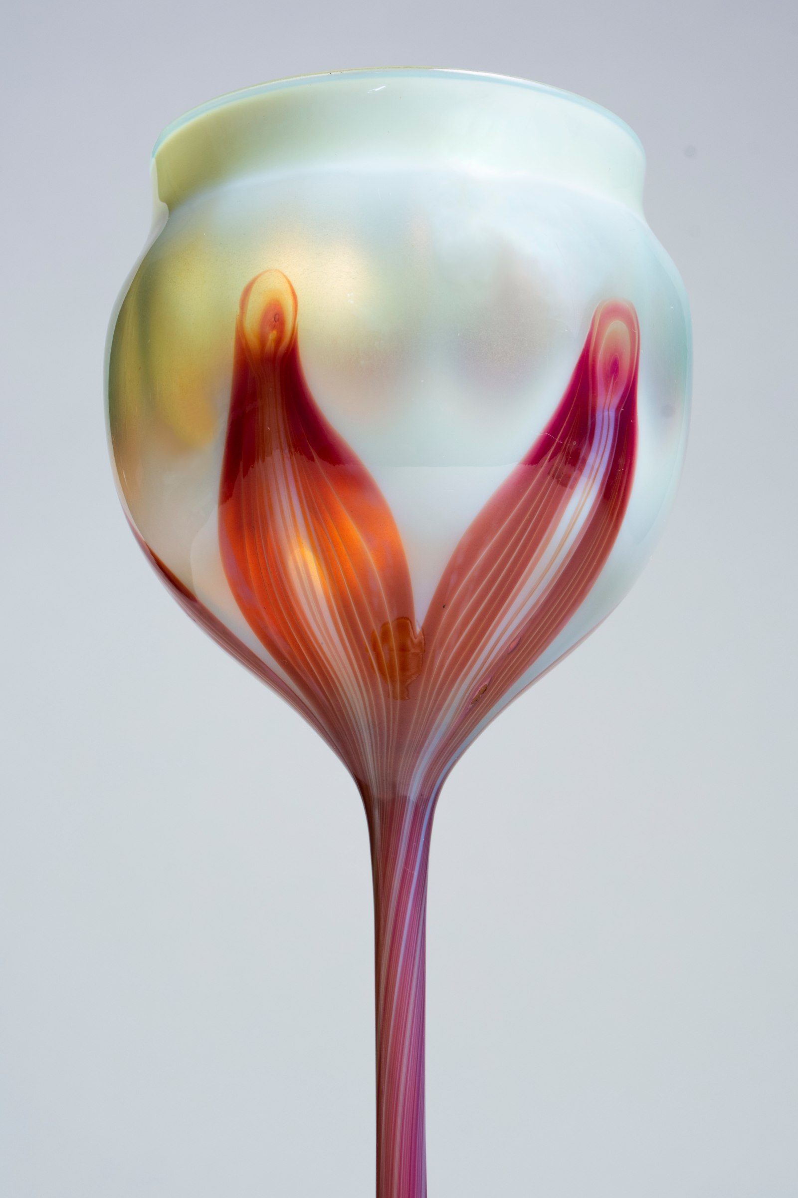 an early tiffany favrile glass flower form, this close up showing the creamy white transparent cup with striated deep red leaf decoration, an unusual color in early tiffany glass