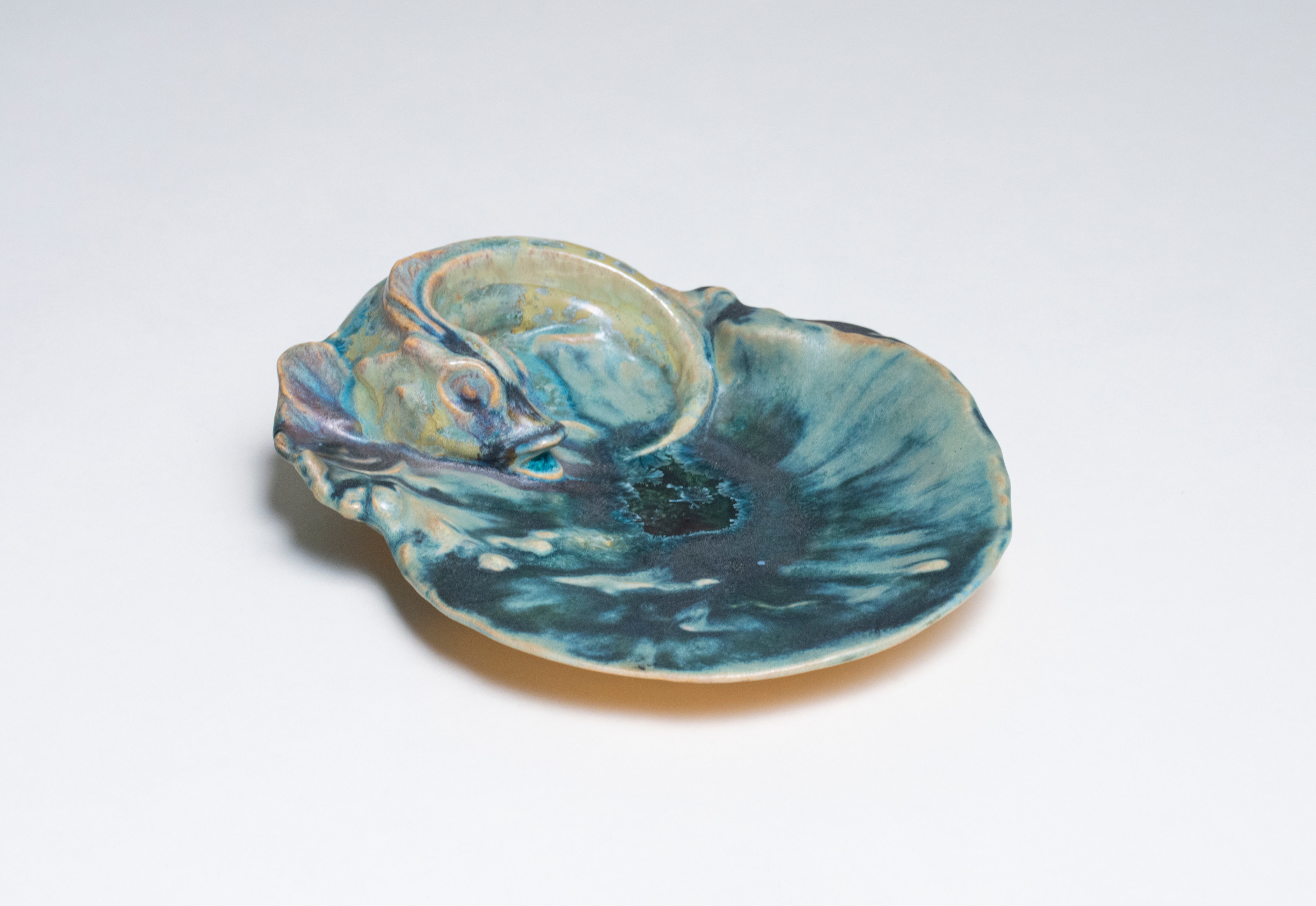 a shallow ceramic dish known as a vide poche (&quot;empty pocket&quot;), in the french art nouveau style here depicting a shallow pool of water (with pooled crystalline glaze) and a sculptural fish perched on the rim