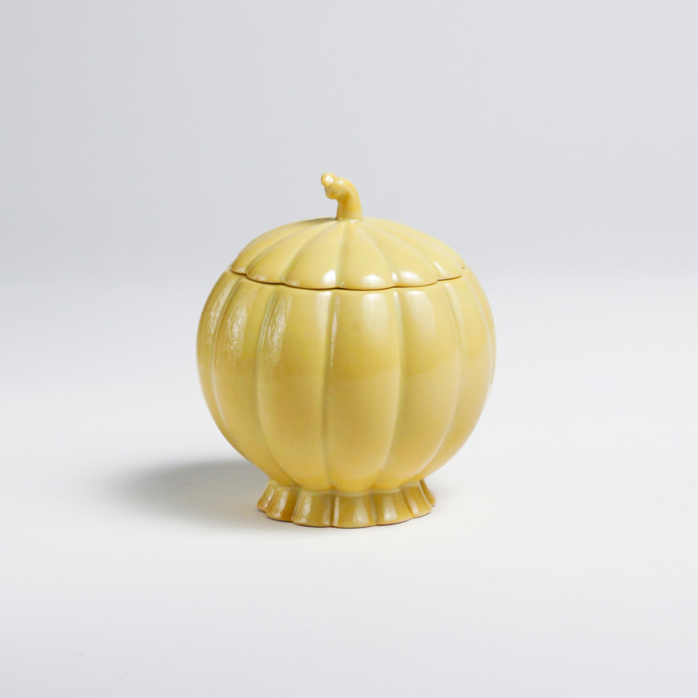 a small circular yellow porcelain sugar bowl in the form of a pumpkin or melon, the lid matching, the finial a curling vine.