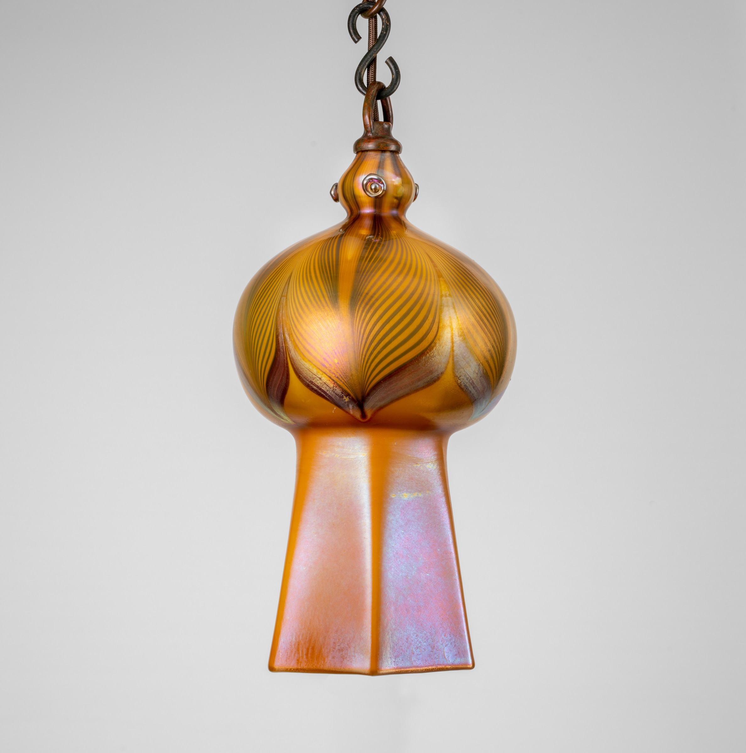 a favrile glass hanging lantern by tiffany studios, iridescent body in the moorish taste decorated with swirling swag motif typical of tiffany glass