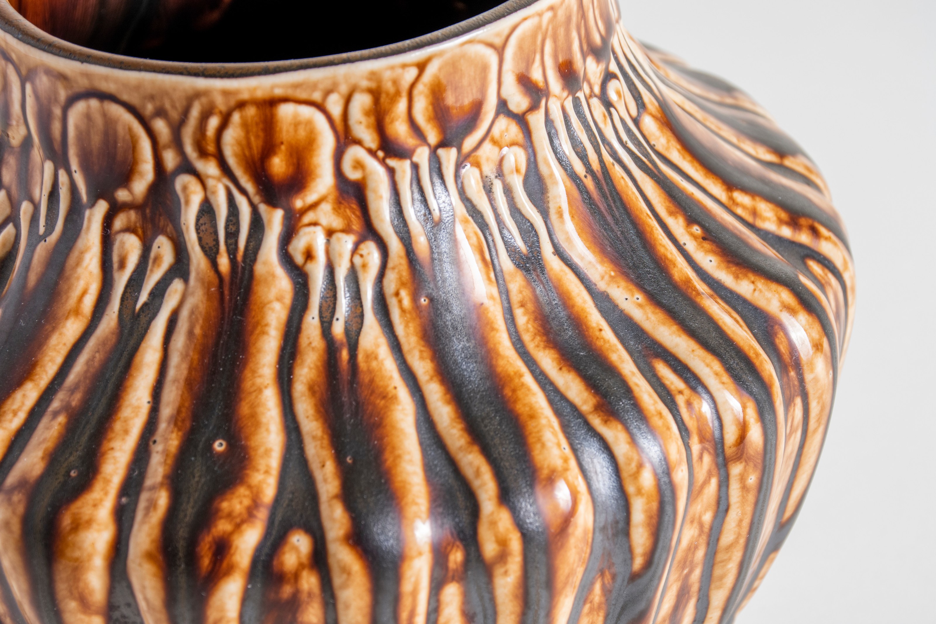 a favrile pottery bowl by tiffany studios, in a dark brown glossy glaze, depicting forest mushroom-like plants or sprouts.