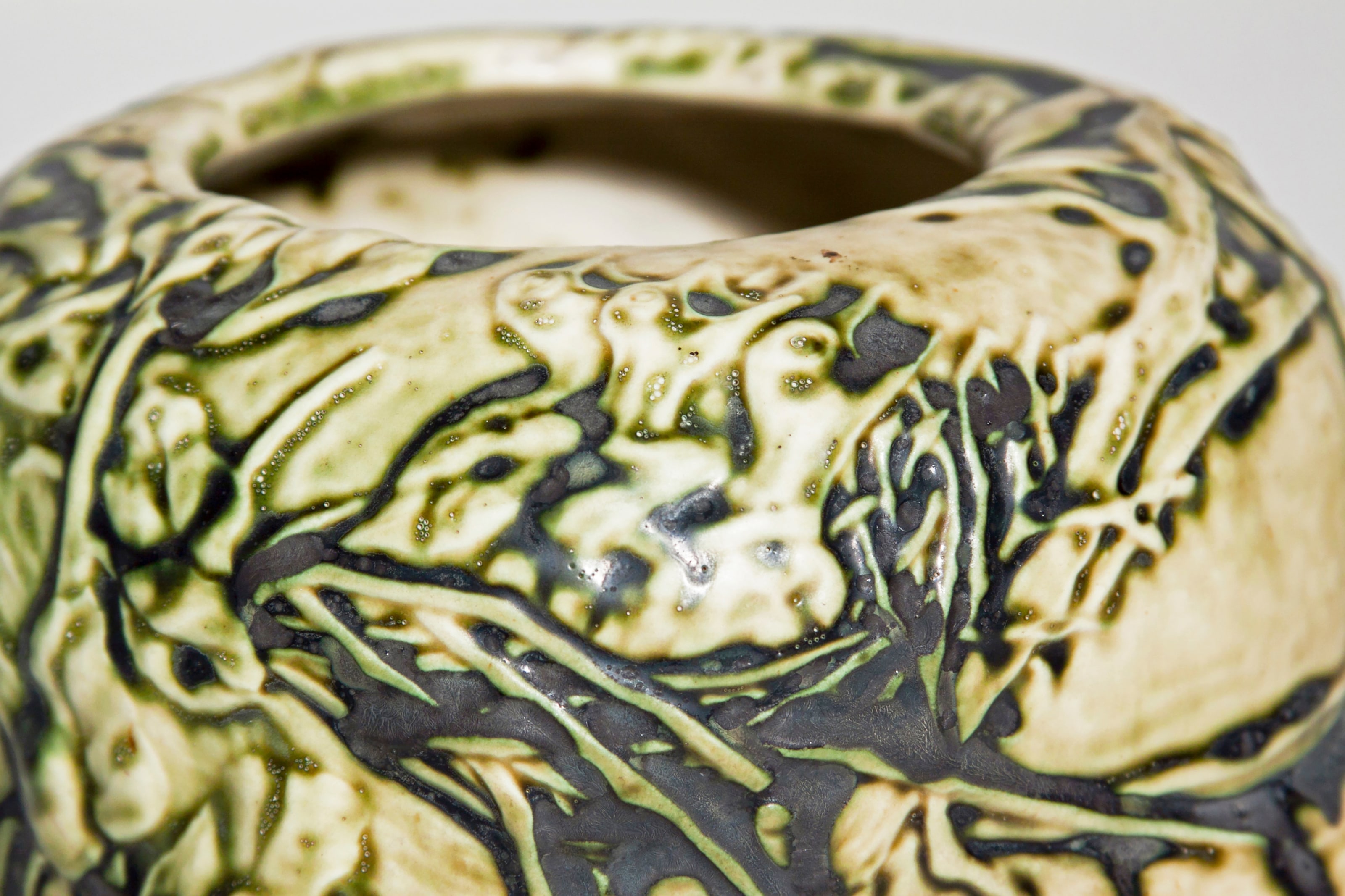 a detail showing the bubbly irregular texture and contrast between high gloss and matte recesses of the tiffany studios old ivory favrile pottery glaze
