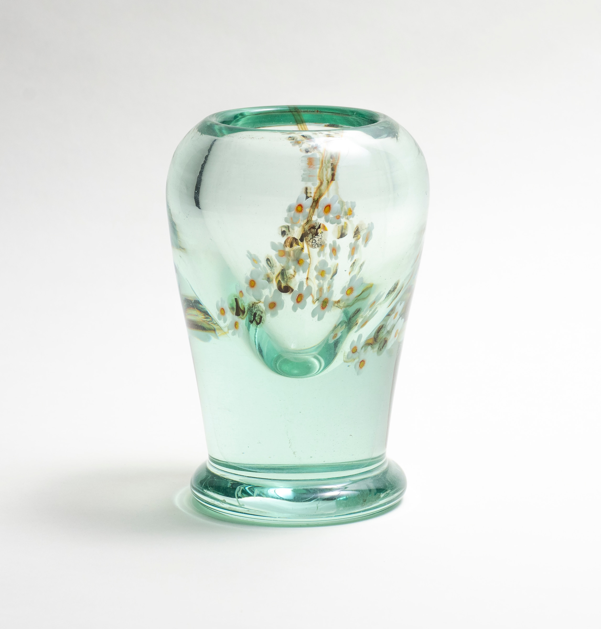 A tiffany favrile glass aquamarine style vase, in which a motif of an apple blossom branch laden with white flowers, all articulated in glass, is encased in a thick layer of clear glass to appear as if floating over a pool of water.