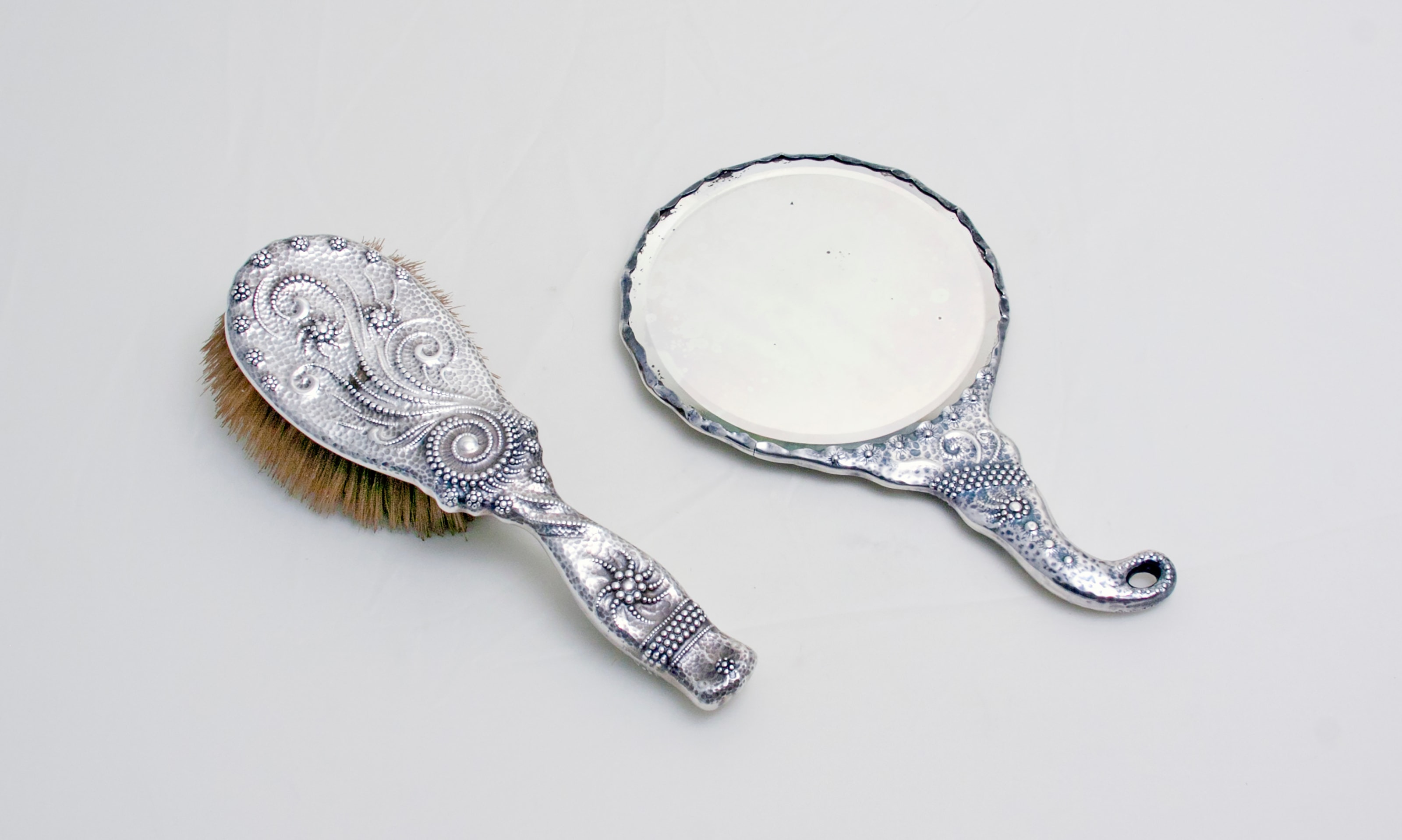 a sterling silver mirror and hairbrush, &quot;vanity set&quot;, in unusual pearled technique by charles osborne for whiting manufacturing company - typical of the aesthetic movement taste
