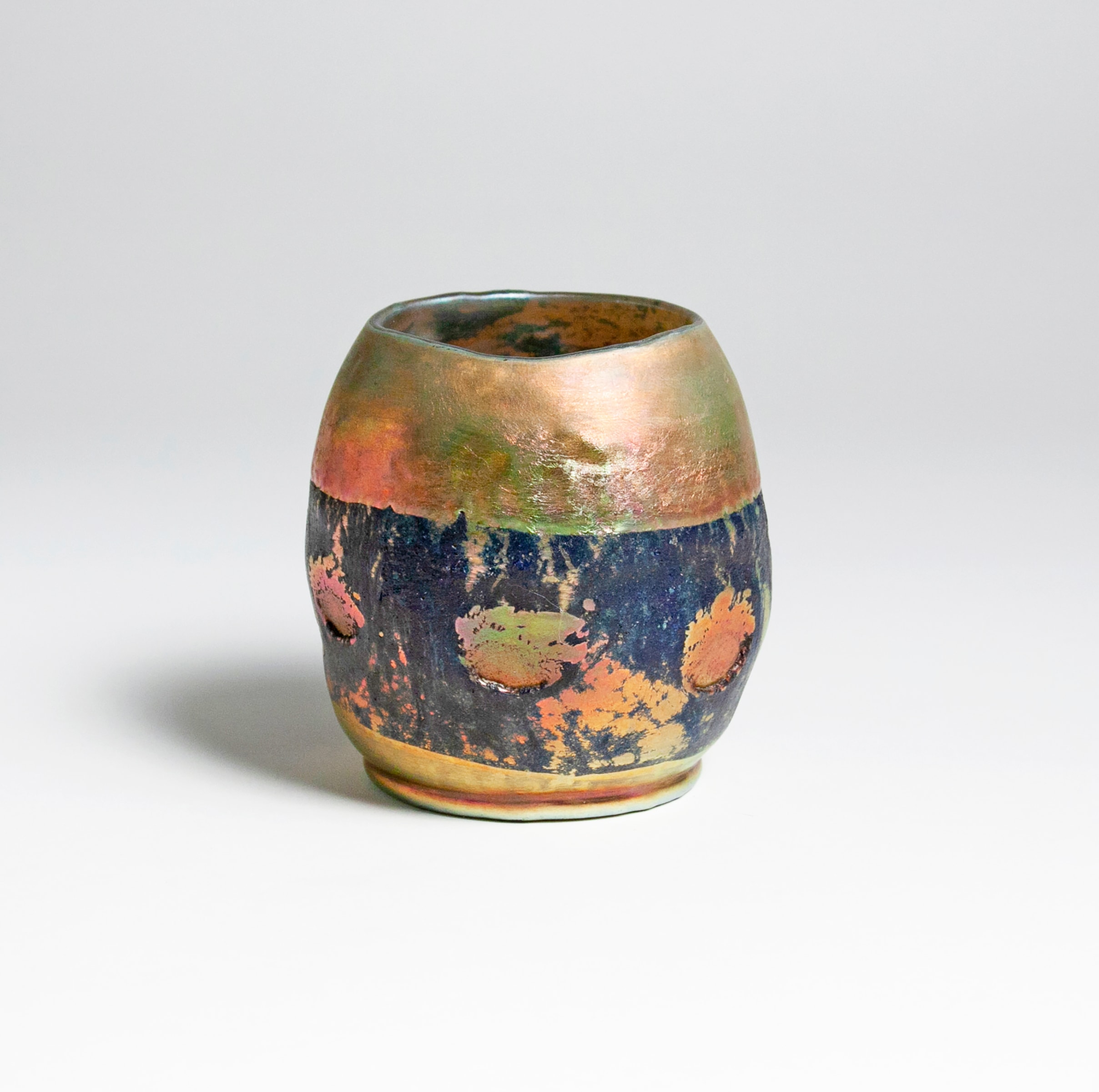 a rare tiffany studios lava favrile glass vase, short irregular cylindrical form recalls japanese raku tea bowls. The body of the vase in gold iridescent glass, a horizontal band of rough textured black matte glass at the center featuring a row of splattered dots of glass in the same gold iridescent.