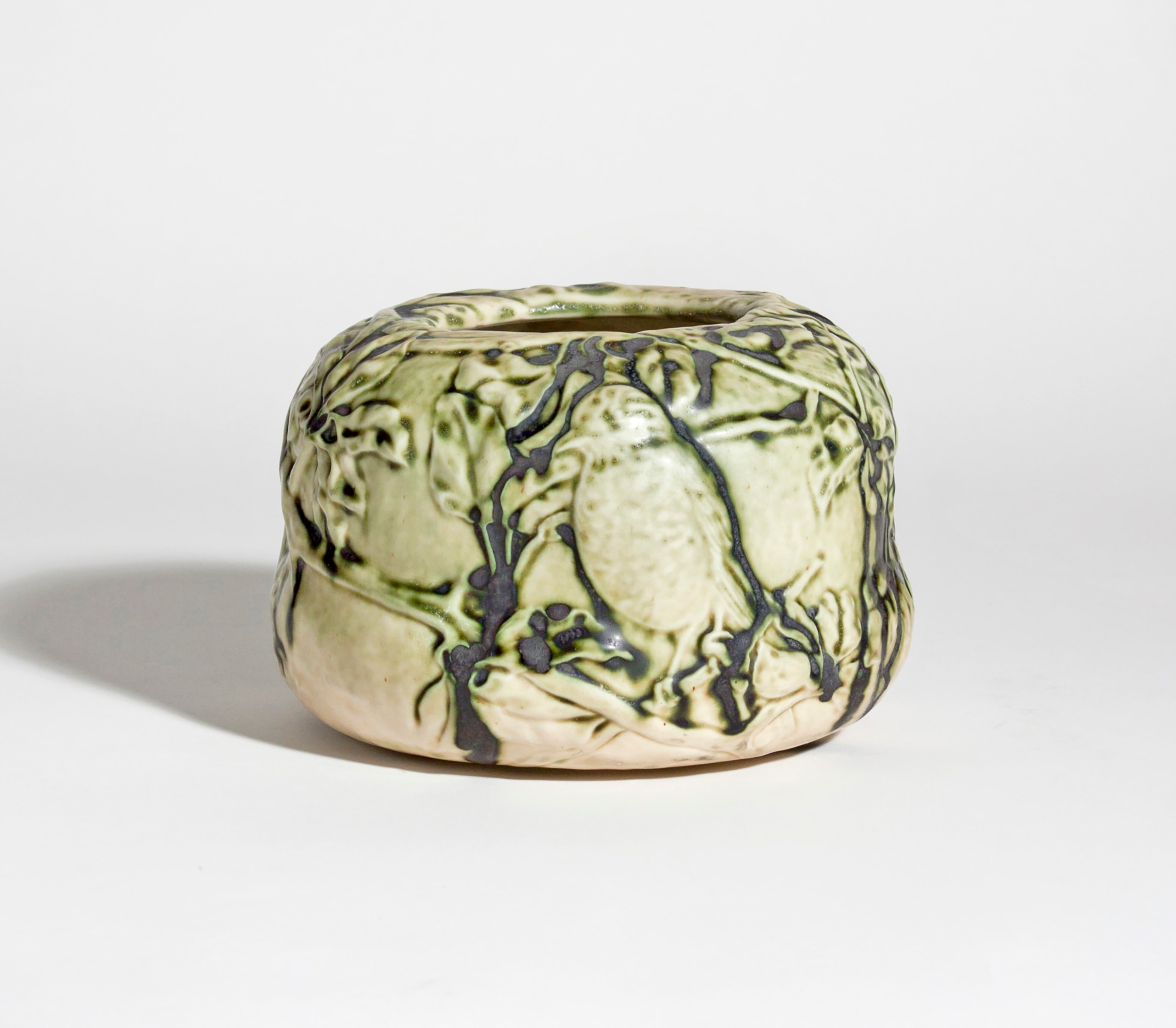 a tiffany favrile pottery bowl of low wide mouth shape, with naturalistic irregular form, in the tiffany old ivory glaze of pale cream with black matte &quot;lowlights&quot;, depicting a mother songbird