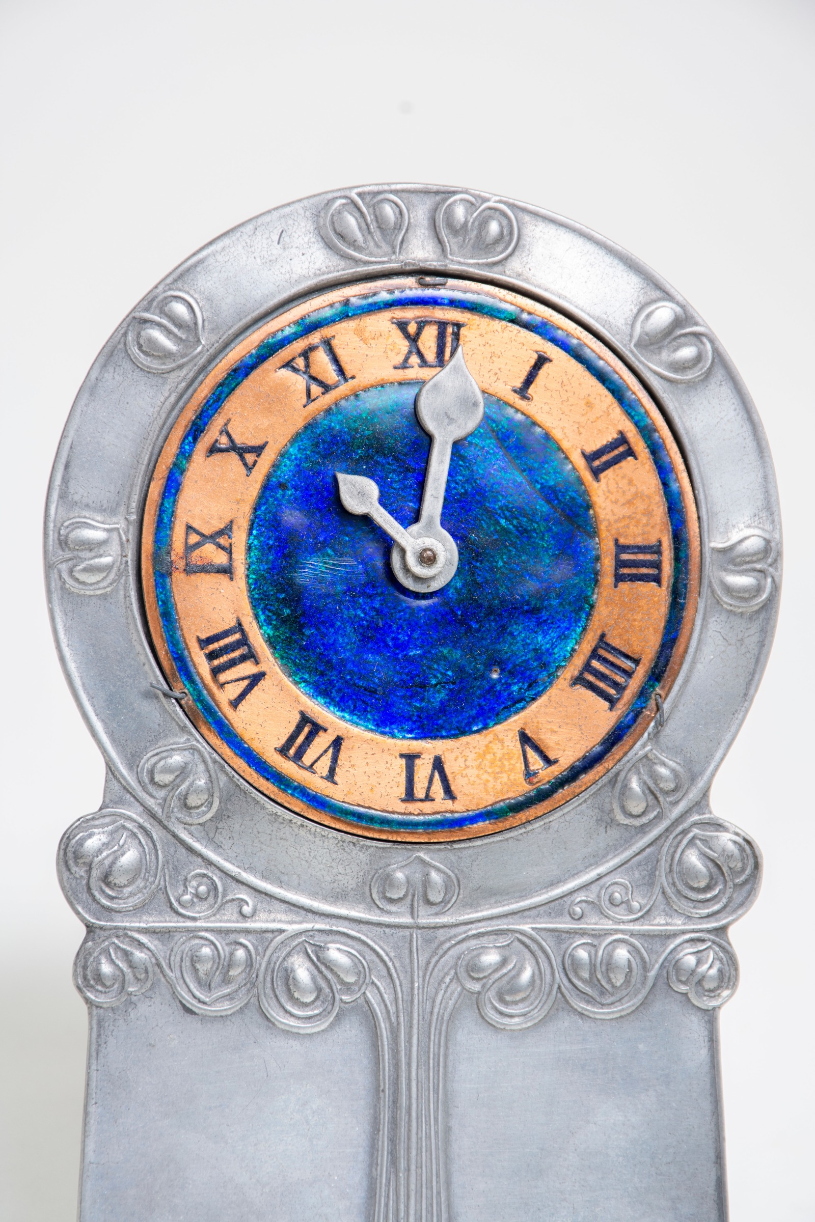detail of the repousse tulip motif and vibrant blue enamel in the clock face of the tudric liberty &amp; company clock circa 1903